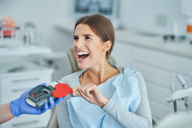 adult woman paying for visit in dentist office