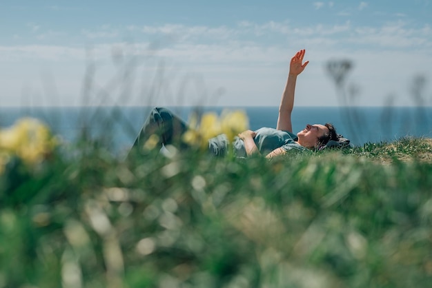 An adult woman a pensioner lies on the grass barefoot with a smile on her face on a sunny day on a