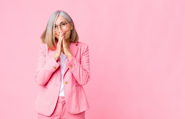 adult woman in pink suit covering mouth with hands giggling with a cute expression