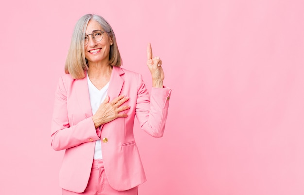 adult woman in pink suit looking happy confident and trustworthy smiling and showing victory