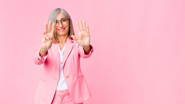 adult woman in pink suit showing number eight or eighth with hand forward