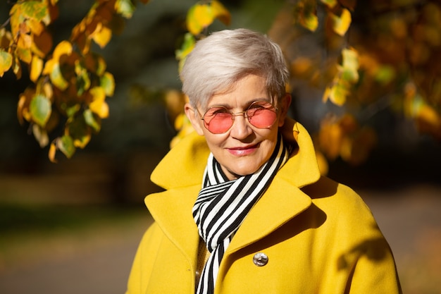 Donna adulta in occhiali da sole rosa nel parco in autunno