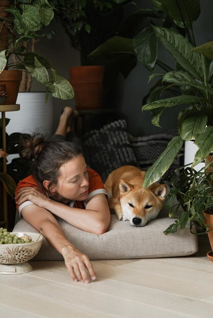 Adult woman resting at home with her best furry friend ginger dog in floral nook biophillia design