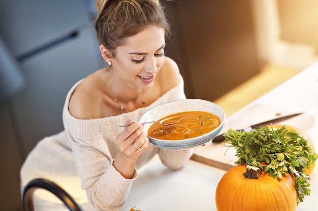 adult woman tasting pumpkin soup in the kitchen