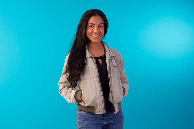 Adult woman wearing casual jacket making facial expressions in studio photo with blue background