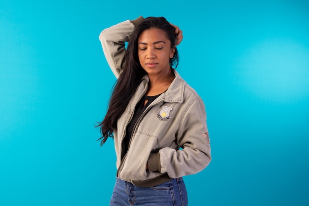 Adult woman wearing casual jacket making facial expressions in studio photo with blue background