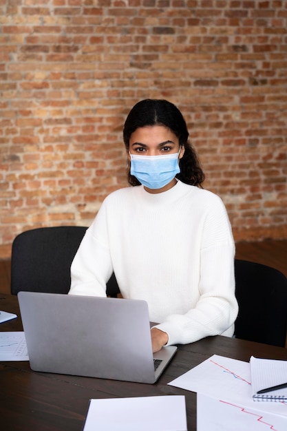 Foto donna adulta che indossa una maschera facciale in ufficio