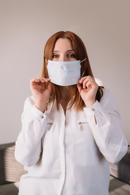 灰色の背景に分離された防護マスクを身に着けている大人の女性。コロナウイルスのパンデミック-covid-19。医療マスク広告
