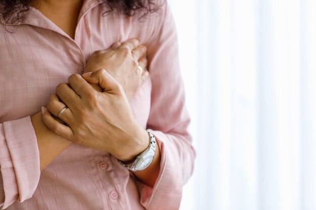 Foto donna adulta con infarto improvviso e usa il petto della stretta della mano con il viso distorto. concetto di assistenza sanitaria di emergenza e affetto da insufficienza congestizia o rianimazione cardiopolmonare, problema cardiaco.