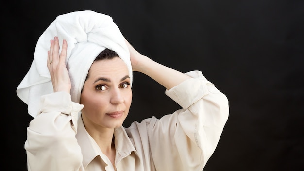 Adult woman with towel wound on her head after shower, black background