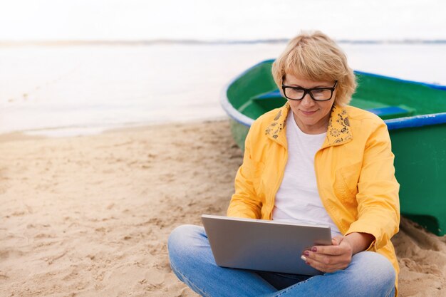 An adult woman works and walks on the beach