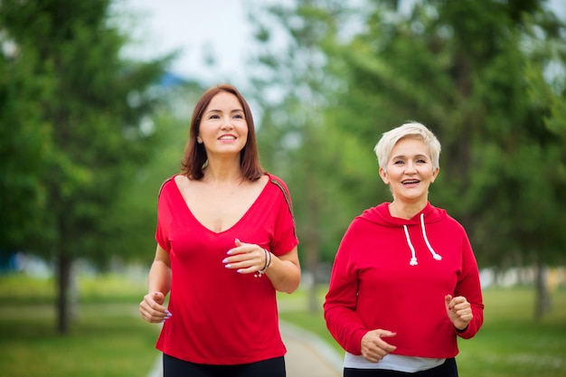 adult women in sportswear run in the summer park