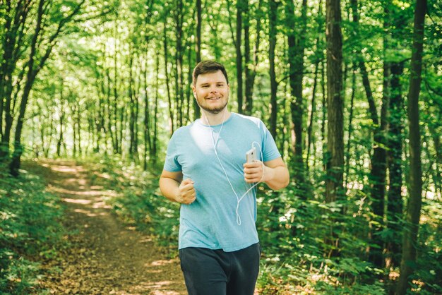 Взрослый молодой человек, бегущий по лесу, копирует пространство, улыбаясь