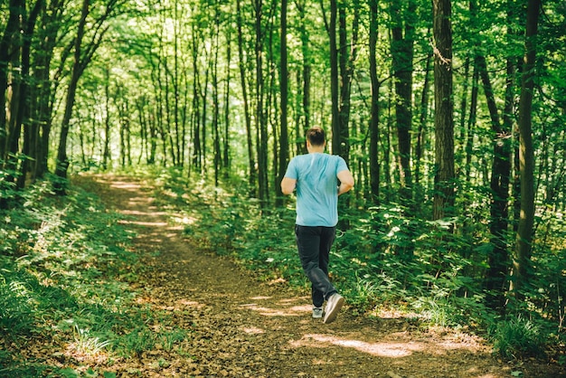 Adult young man running in woods copy space