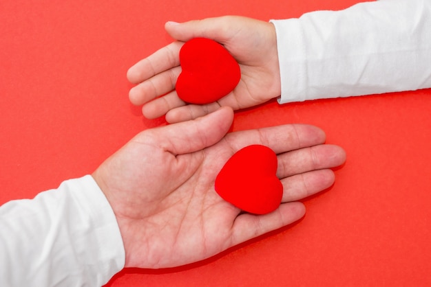 Adults and children hands holding red heart, health care love,\
give, hope and family concept, world heart day, world health\
day