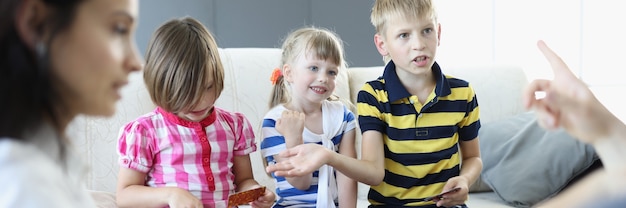 Adults and children sit around a table on which playing cards are located boy argues