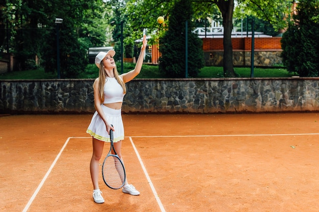 Advanced confident female tennis player takes a forehand swing\
at the ball at open summer open court.