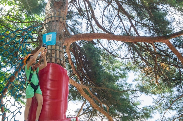 Adventure climbing high wire park - people on course in mountain helmet and safety equipment