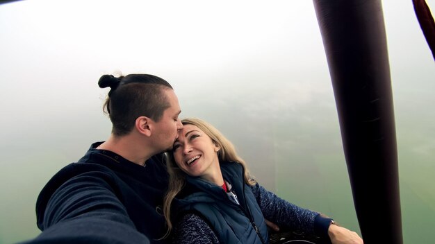 Adventure love couple on hot air balloon watermelon man and\
woman kiss hug love each other burner directing flame into envelope\
happy people