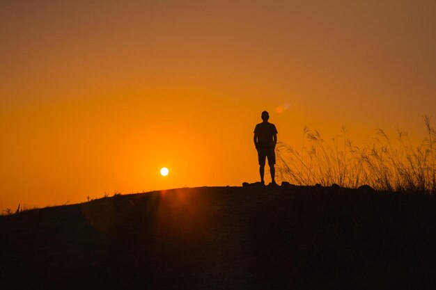 Adventure travel from silhouette man hiking and stand on top of the mountain in summer season