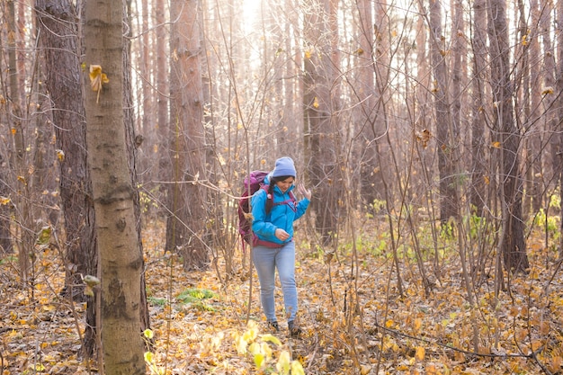 Приключения, путешествия, туризм, походы и люди концепции - улыбающаяся женщина, идущая с рюкзаками на осеннем естественном фоне.