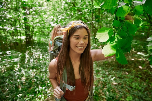 Foto concetto di avventura, viaggio, turismo, escursione e persone - gruppo di amici sorridenti che camminano con gli zaini nei boschi