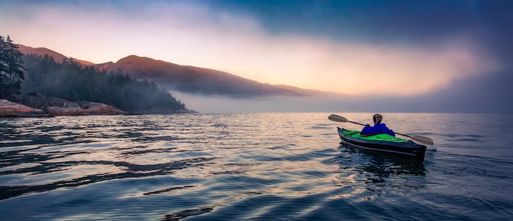 Photo adventure woman in kayak watching sunset on ocean coast