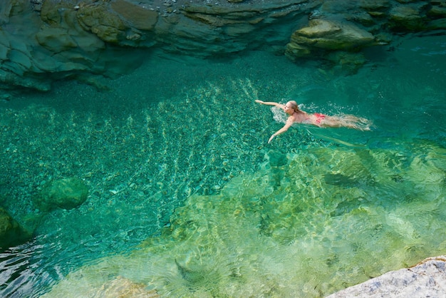 Adventure woman swim through surreal exotic paradise blue river\
on wanderlust travel vacation adventure woman swim through surreal\
exotic paradise blue river on wanderlust travel vacation