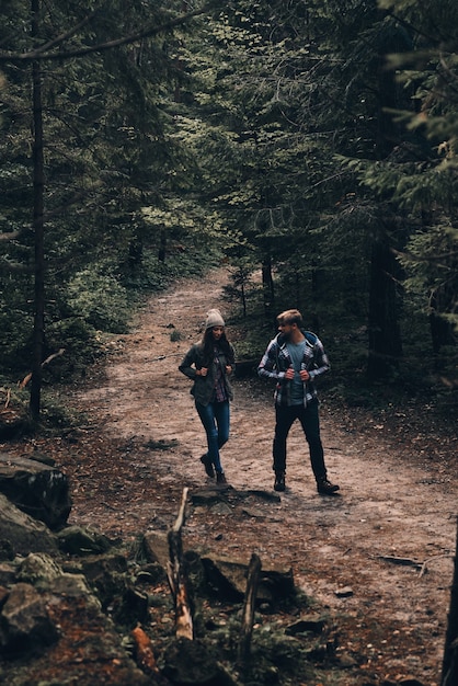 Adventurous couple. Full length of beautiful young couple hiking together in the woods while enjoying their journey