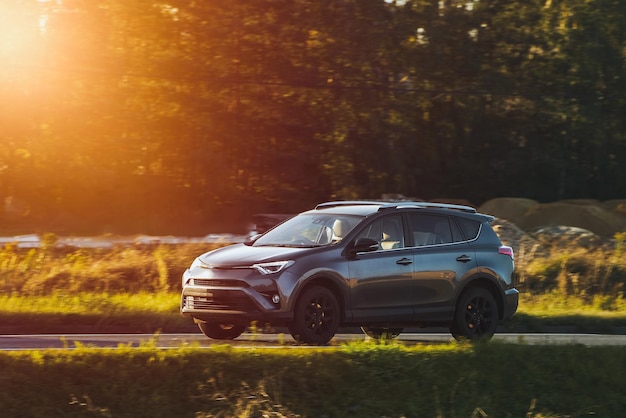 An adventurous drive as a crossover SUV car speeds along a highway under the beautiful sunlight and surrounded by nature beauty
