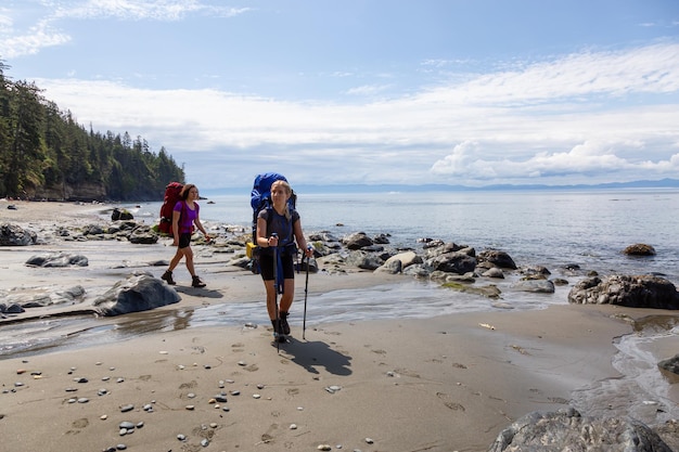 Adventurous friends are hiking Juan de Fuca Trail on Mystic Beach at the Pacific Ocean Coast