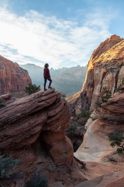 Adventurous Girl at the edge of a cliff is looking at a canyon landscape Utah