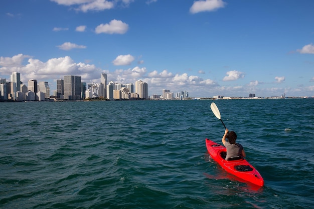 Adventurous girl kayaking in front of a modern Downtown Cityscape