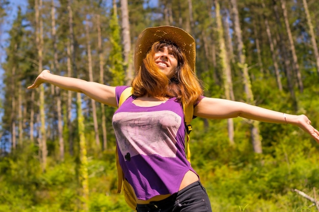 An adventurous hiker smiling next to some pine trees in the forest