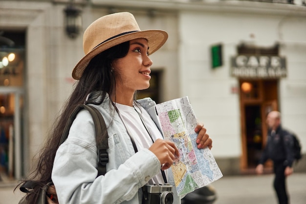 Foto avventurosa turista latina esplora la nuova città con la macchina fotografica