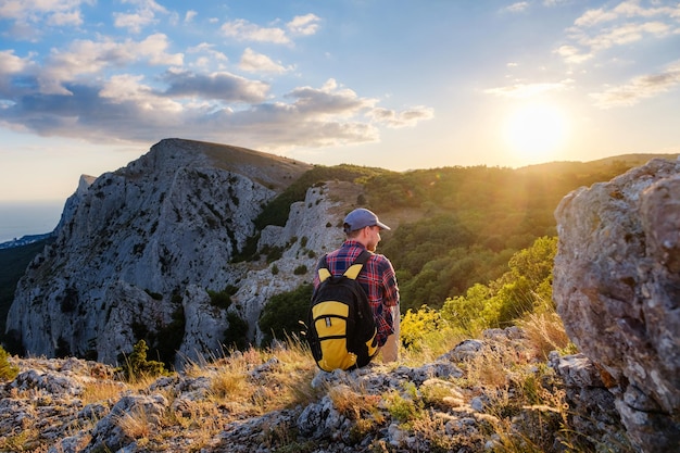 L'uomo avventuroso è in cima alla montagna e si gode la splendida vista durante un tramonto vibrante