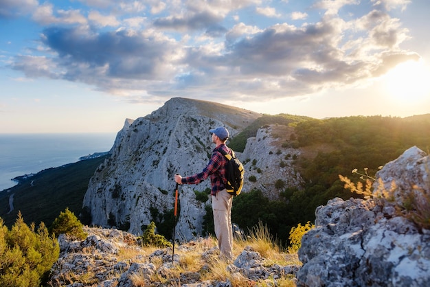 Adventurous man is on top of the mountain and enjoying the beautiful view during a vibrant sunset