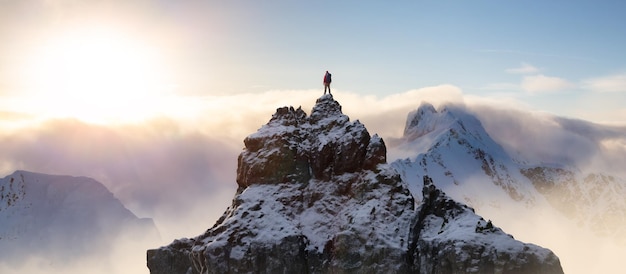 Фото Авантюрный человек, стоящий на вершине горного утеса, драматический экстремальный приключенческий комплекс