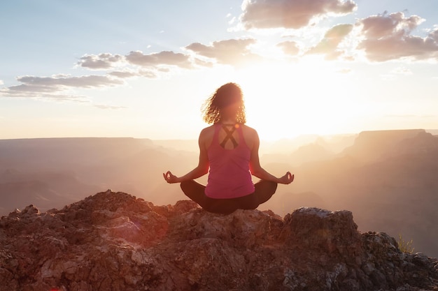 Adventurous traveler woman doing meditation on desert rocky mountain american landscape