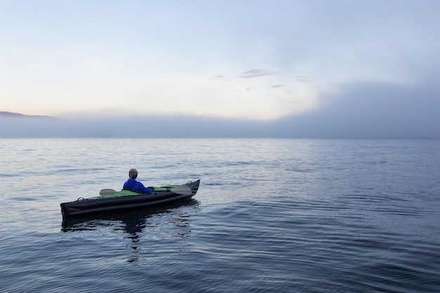 Adventurous woman is sea kayaking on an inflatable kayak