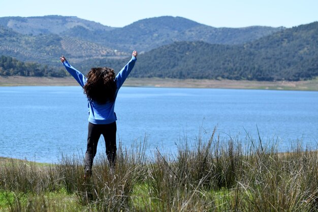 Adventurous woman jumping with lake in the background freedom concept