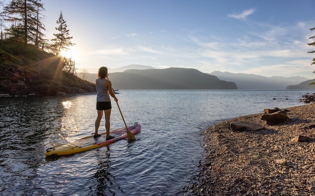 Adventurous woman paddling on a paddle board in a peaceful lake