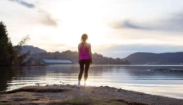 Photo adventurous woman on a shore enjoying colorful sunset