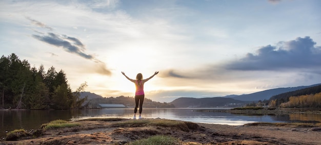 Adventurous Woman on a shore enjoying colorful Sunset