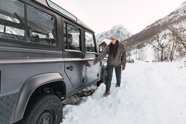 イタリア北部の雪に覆われたアルプスの山で彼女の車に入る冒険的な若い女の子。