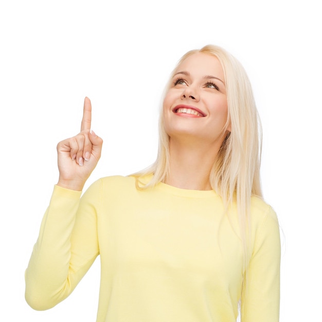 advertisement concept - attractive young woman in casual clothes pointing her finger up