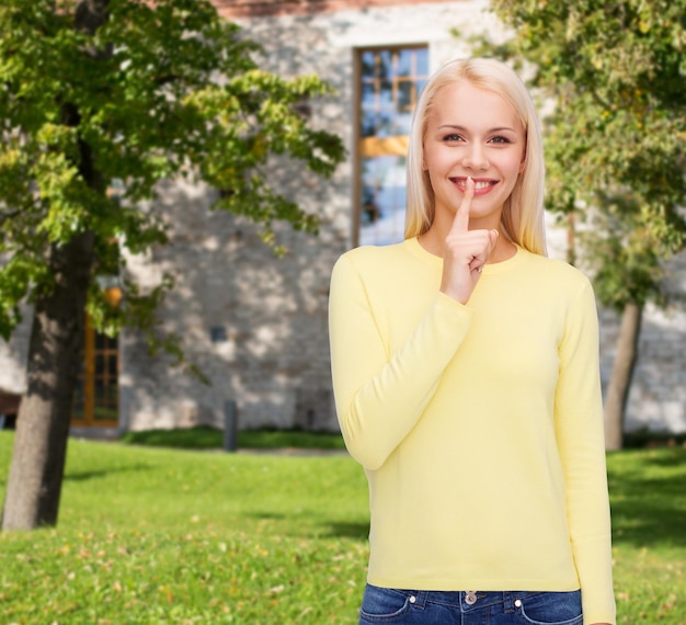 advertisement concept - attractive young woman with finger on her lip