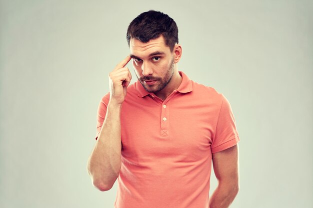 Photo advertisement, idea, inspiration and people concept - man pointing finger to his temple over gray background