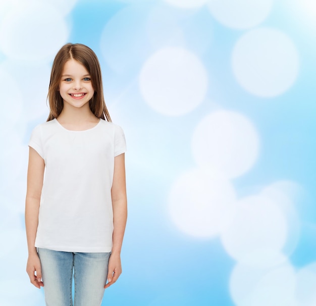 advertising, childhood and people - smiling little girl in white blank t-shirt over blue background