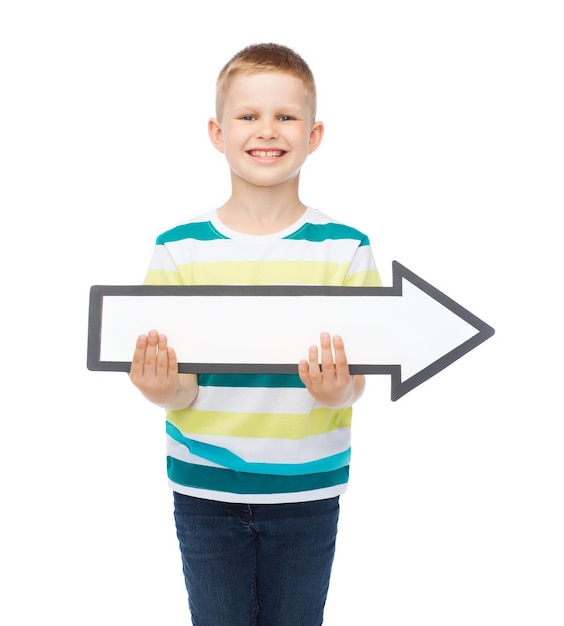 advertising, direction and childhood concept - smiling little boy with white blank arrow pointing right